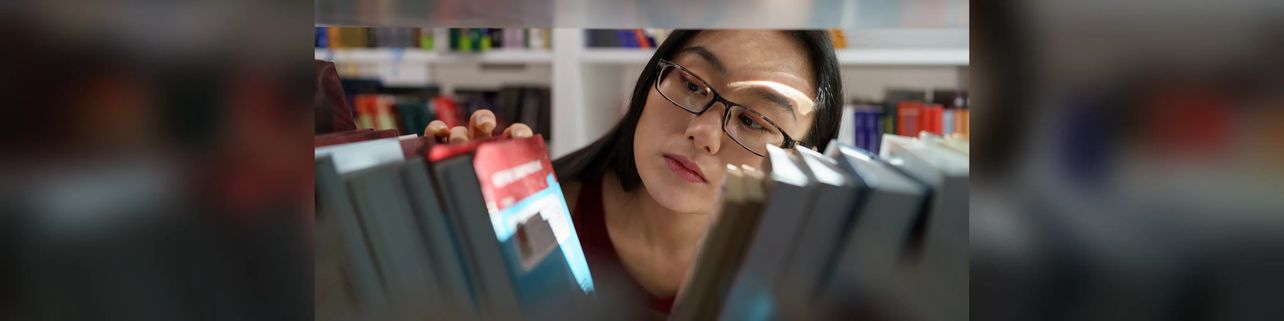 Person browsing books on a bookshelf.